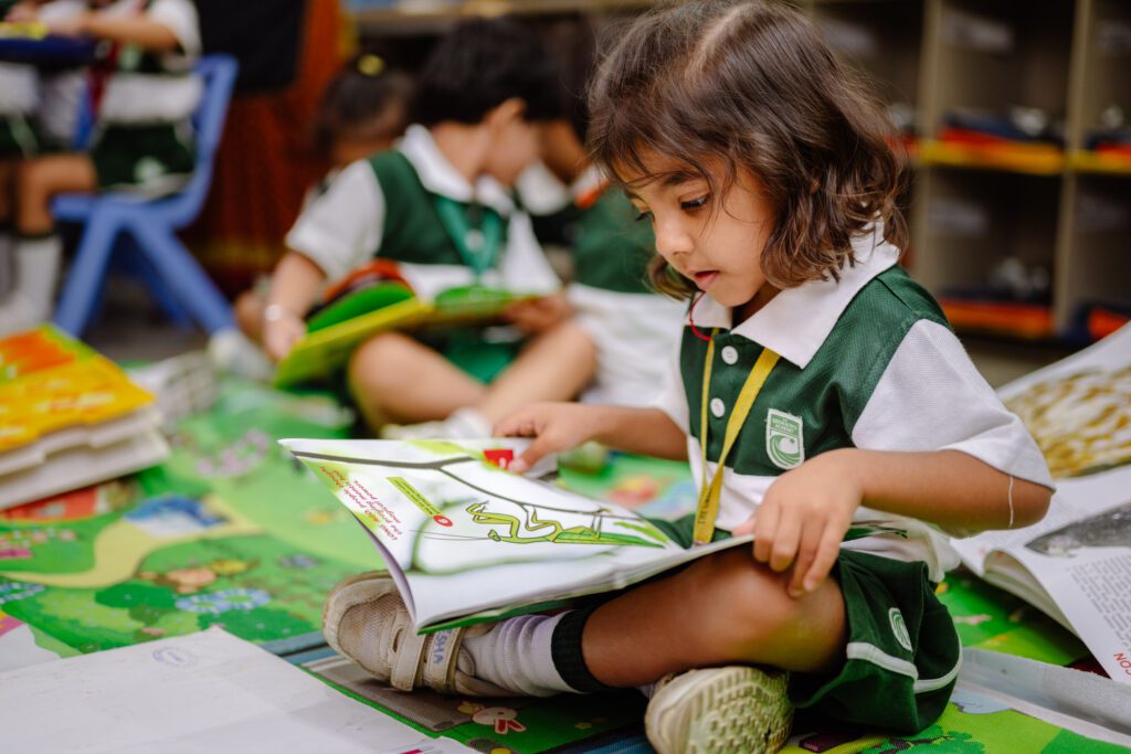 TGAA pre-primary school student sitting with a book.