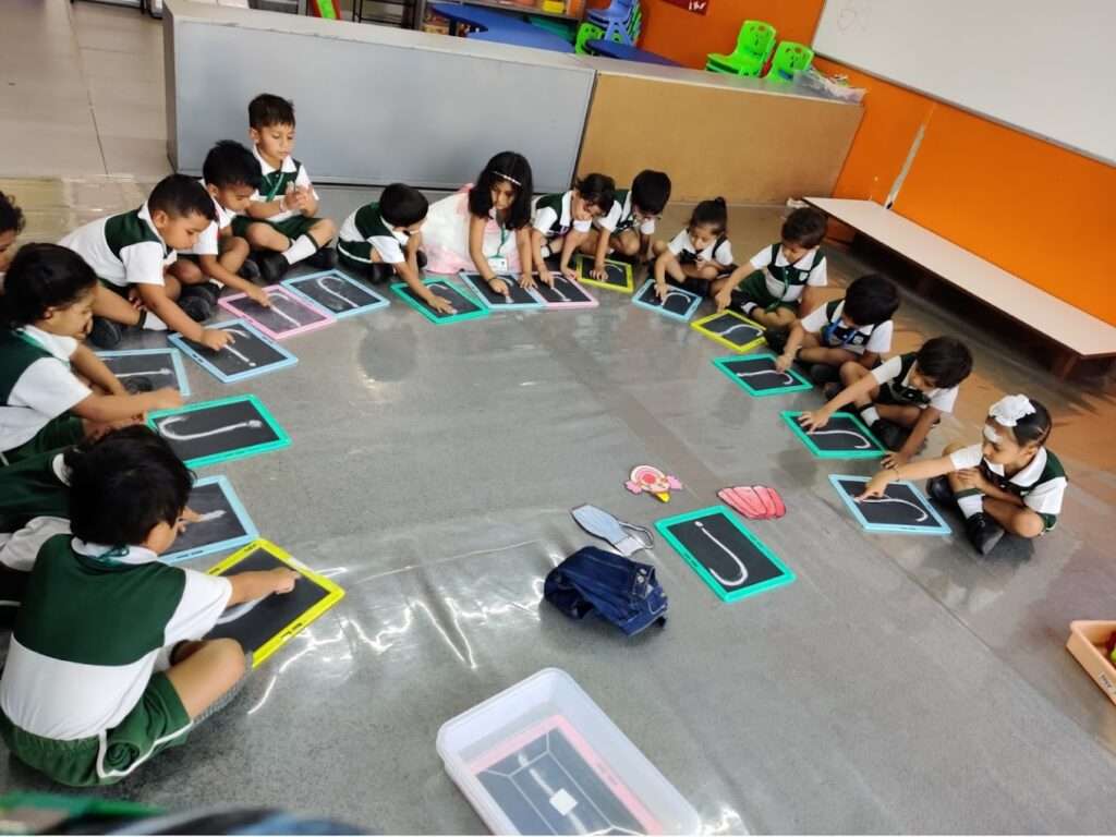 TGAA pre-primary students learning alphabets on the slate.